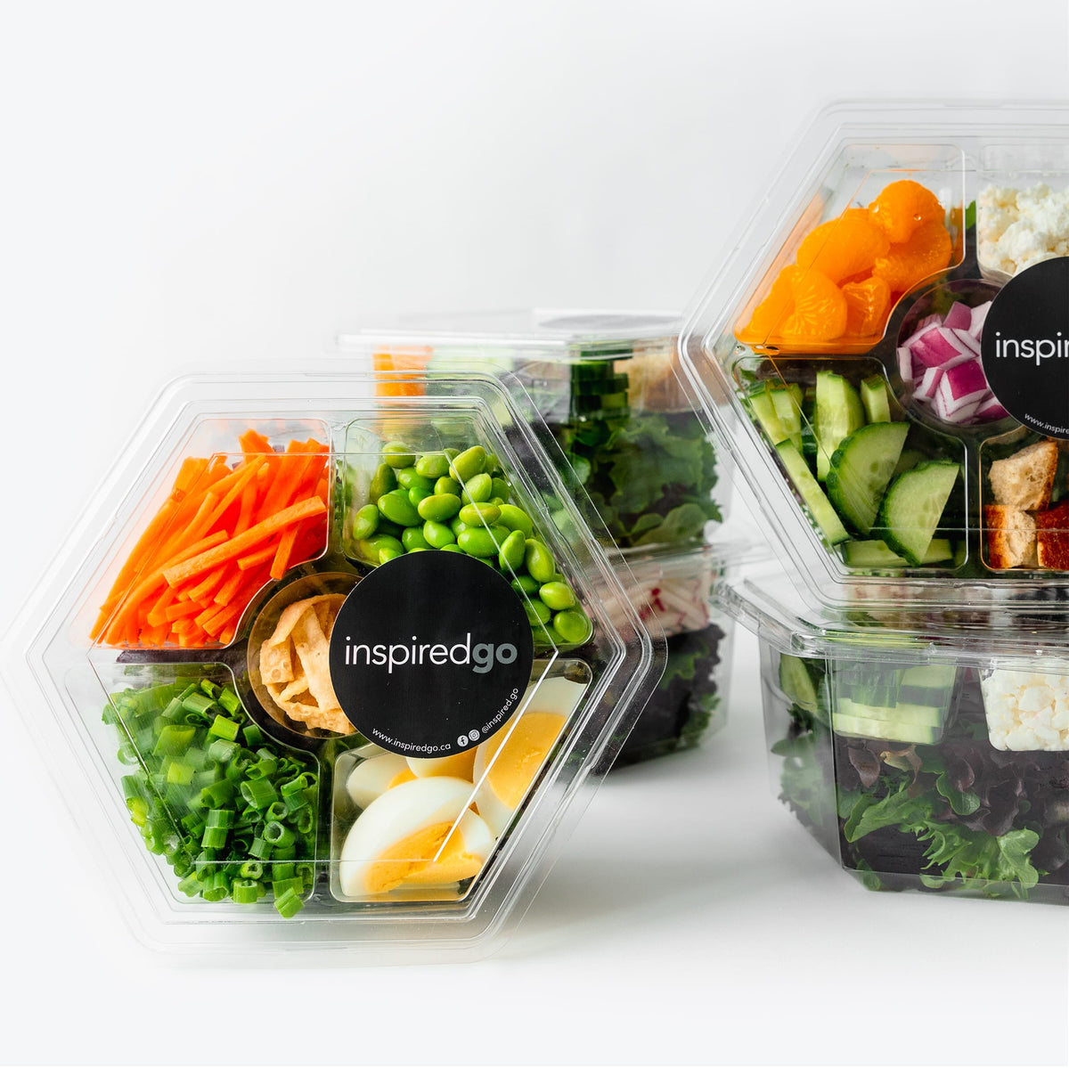 Hexagonal salad containers with fresh ingredients on a white background, featuring the brand 'inspiredgo'.